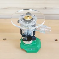 6-inch round clear acrylic base plate with brass center bushing mounted on green Metabo trim router