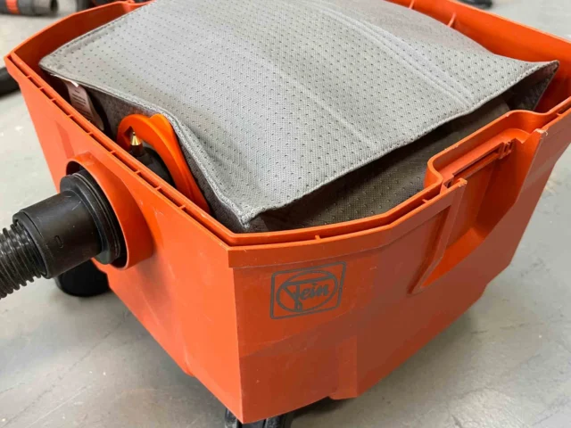 Macam reusable dust bag installed in an orange FEIN Turbo dust extractor, showing gray polyester fleece filter surface