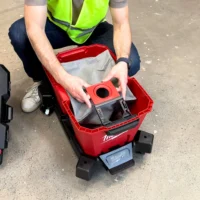 Red polyester dust bag with circular inlet opening, held over a Milwaukee M18 Fuel Nexus vacuum tank