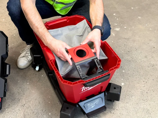 Red polyester dust bag with circular inlet opening, held over a Milwaukee M18 Fuel Nexus vacuum tank