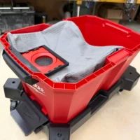 Red Macam reusable dust bag with gray fabric insert inside, displayed empty in a red and black Milwaukee M18 Packout vacuum bin