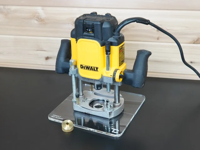 DeWalt 625 plunge router mounted on a 10-inch clear acrylic guide bushing base plate, brass knob beside it