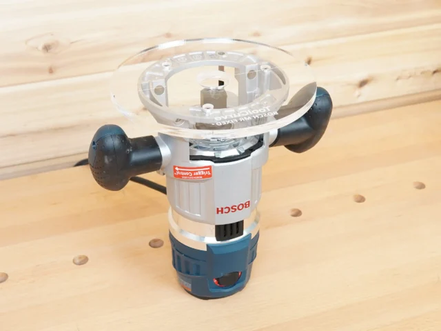 8-inch clear acrylic router base plate mounted on a Bosch MR23EVS plunge router, showing the large round base and factory tool heads