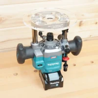 Clear 8-inch round acrylic router base plate mounted upside down on a Makita 40v plunge router