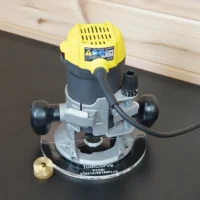 Ryobi R1631G router on an 8-inch clear acrylic round base plate marked ToolCurve, brass guide bushing beside it