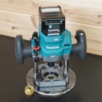 Makita 40v XGT plunge router mounted on an 8-inch clear acrylic guide bushing base plate, brass bushing beside it