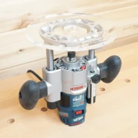 8-inch acrylic router base plate mounted on a Bosch plunge router, showing the clear round platform and guide bushing opening from above