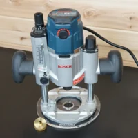 Bosch MR23EVS plunge router fitted with an 8-inch clear acrylic wide cut round base plate, brass insert alongside