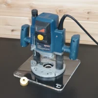 Bosch 1613EVS plunge router mounted on a 10" clear acrylic guide bushing base plate, with brass ring alongside
