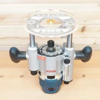 8-inch clear acrylic router base plate attached to Bosch MR23EVS plunge router, shown from above on wood surface