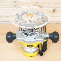 Clear acrylic 8-inch router base plate mounted on yellow Dewalt DW618 plunge router, viewed from above showing brass center insert and mounting hardware