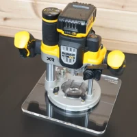 10-inch square clear acrylic base plate attached to a DeWalt 20v XR cordless router, shown on a display stand with battery and charger