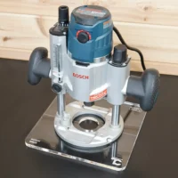 10-inch square clear acrylic base plate attached to a Bosch MR23EVS plunge router, shown from above on a workbench