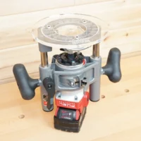 8-inch clear acrylic router base plate mounted on a Milwaukee M18 2-1/4HP router, showing wide circular platform and dual handles