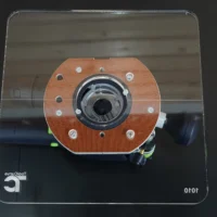 10-inch square clear acrylic base plate with orange center ring and bolt holes, mounted on a Festool OF 1010 router