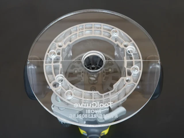Clear acrylic round base plate with 8-inch diameter, mounted on Ryobi 1-1/2" router, viewed from above showing center spindle hole and eight mounting holes