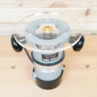 8-inch round acrylic router base plate with brass center threaded insert and guide bushing compatible design, mounted on a Porter Cable 690 series router, showing the clear acrylic underside with grip handles on both sides