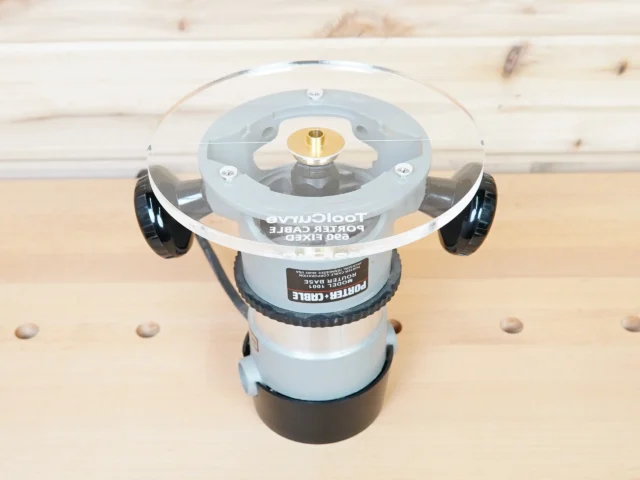 8-inch round acrylic router base plate with brass center threaded insert and guide bushing compatible design, mounted on a Porter Cable 690 series router, showing the clear acrylic underside with grip handles on both sides