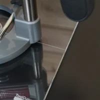 Clear acrylic 10-inch square base plate attached to Milwaukee M18 router, showing smooth underside and mounting interface