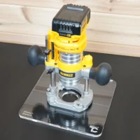 10-inch square clear acrylic router base plate mounted on a DeWalt DNP612 plunge router, installed on a ToolCurve mounting plate