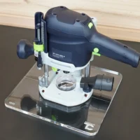 Clear acrylic base plate mounted on a Festool OF 1010 router, shown on a transparent display stand