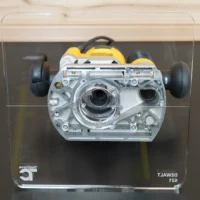 Clear acrylic square router base plate attached to DeWalt 621 plunge router, front view showing dual hose ports and mounting holes