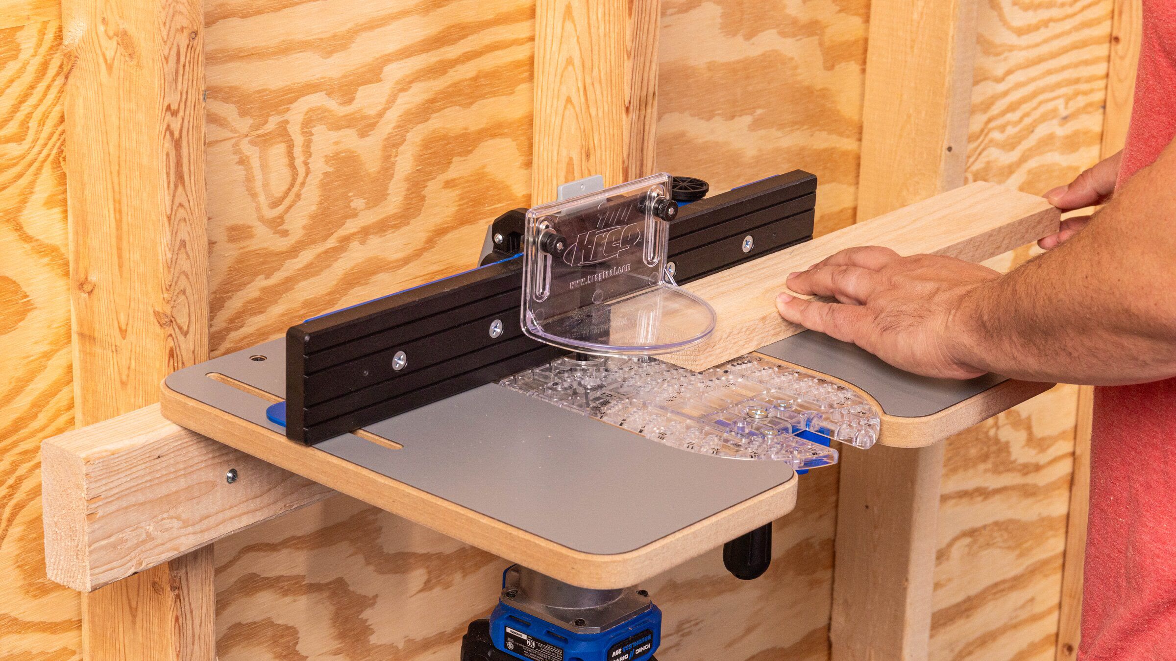 Kreg Dock & Go trim router table secured to a wall support while a board is guided along the fence